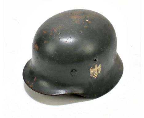 A German WWII Wehrmacht helmet bearing eagle and swastika decal, retaining leather liner and canvas chin strap, length 28.8cm