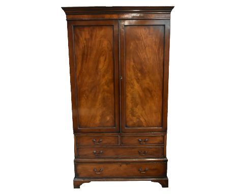 An early 20th century mahogany twin door wardrobe, the pair of panelled doors above two short and one long dummy drawer and o