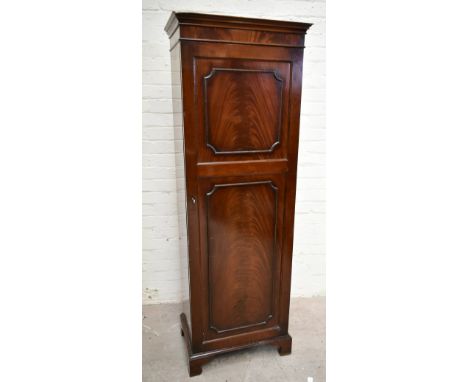 A 1950s mahogany veneered single door wardrobe, the single panelled door with mirror to the interior and hanging rail, raised