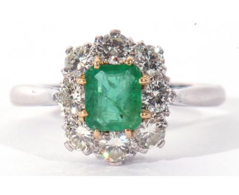 Emerald and diamond cluster ring featuring a rectangular step cut emerald, claw set and raised within a diamond surround, dia