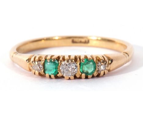 Antique diamond and emerald ring featuring three graduated old cut diamonds and two cushion cut emeralds, all in a carved set