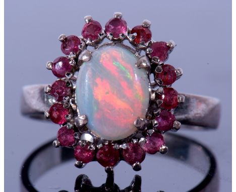 Modern opal and ruby cluster ring, the oval cabochon opal 8 x 6mm set within a small round ruby surround (16), stamped 18K, s