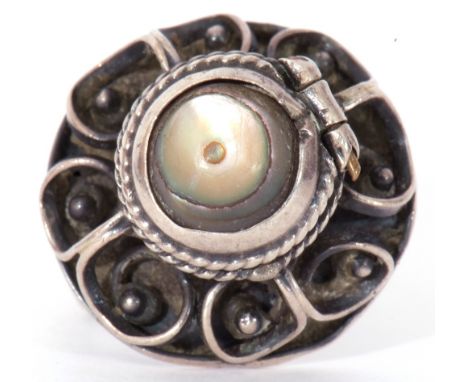 White metal filigree poison ring, the hinged mother of pearl lid opening to a vacant reservoir, stamped verso "925", size H