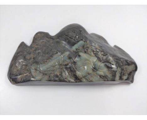 A jade carving depicting a mountain range and carving of flora and fauna. 