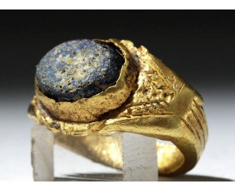 Ancient Rome, ca. 1st to 3rd century CE. An 18 karat gold ring with a deep blue glass intaglio set in an oval bezel. The gold