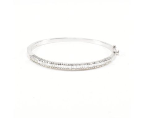 A hallmarked 18ct white gold and diamond hinged bangle. The bangle set with approximately fifty baguette cut diamonds. Estima