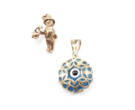 Two gold novelty pendant charms. A gold and blue glass enamel painted eye pendant with bale atop stamped 585. Together with a