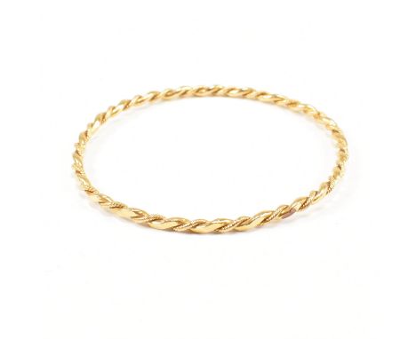 A vintage yellow metal bangle bracelet. The bangle of rounded form comprised of a polished and twisted twist effect band. Unm