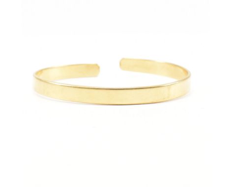 A vintage hallmarked 18ct yellow gold bangle bracelet. The bangle of cuff form having a straight band and curved terminals. H