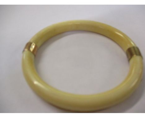 A 1920's ivory bangle with yellow metal vein running through the entire circumference and two yellow metal bands, testing as 