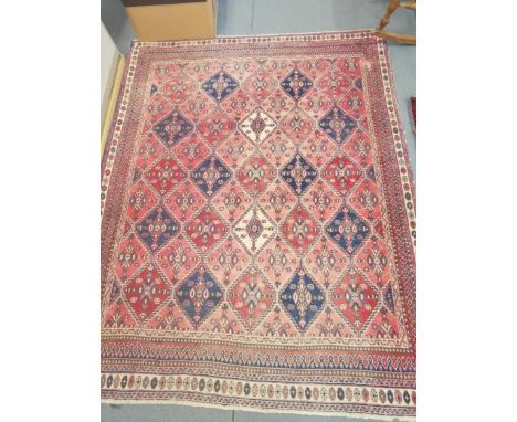 A vintage Qashqai carpet with repeating geometric medallions, on a red ground, contained by geometric border 215cm x 170cm Lo