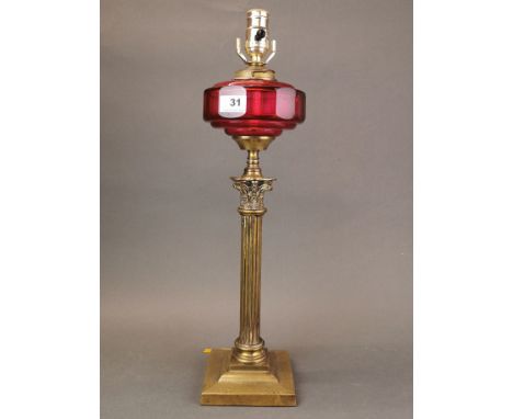 A 19th century gilt brass and ruby glass column oil lamp converted for electricity, H. 56cm.