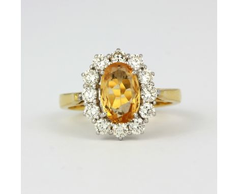 A hallmarked 18ct yellow gold cluster ring set with a large oval cut orange topaz, approx. 1.67ct, surrounded by brilliant cu