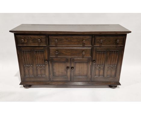 Ercol oak dresser base&nbsp;having a combination of four drawers and three cupboards, the cupboard doors with linen fold pane