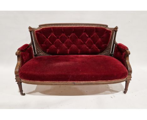 Late Victorian carved walnut two-seater salon sofa, upholstered in buttonback red velvet, with gadrooned and foliate carved f