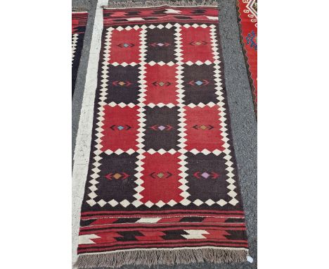 Two vintage Afghan rugs, each with chequerboard design in red and dark brown within cream lozenge-shaped borders, 193cm x 97c