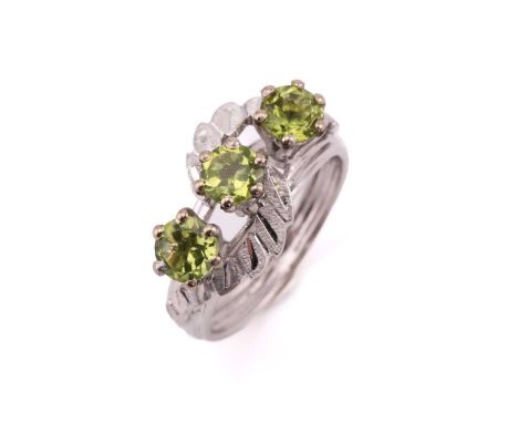 A three-stone peridot ring, comprises three round peridots each approximately measuring 4.7 mm, claw set on a white metal hig