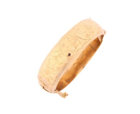 A 9ct yellow gold hollow hinged bangle with safety chain, one side is engraved with scrolling filigree design, 'Vera, with lo