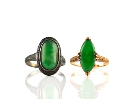 Two jade rings, one comprises a marquise-shaped chrome green jadeite cabochon claw set on a yellow metal mount, with engraved