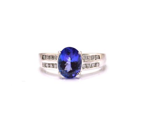 An 18ct white gold tanzanite and diamond dress ring, featuring an oval fancy cut tanzanite with an intense purplish-blue body