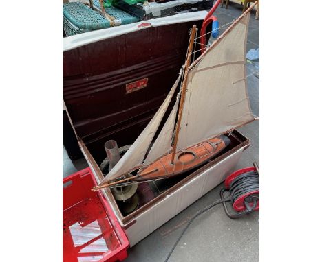 A tin trunk and contents including a vintage 1954 Triang pedal scooter, a model sail boat and a brass paraffin lamp. 