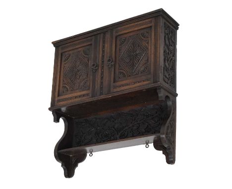 Early 20th Century oak hanging cupboard, with single shelf over foliate carved panel and two carved and fielded panel doors e