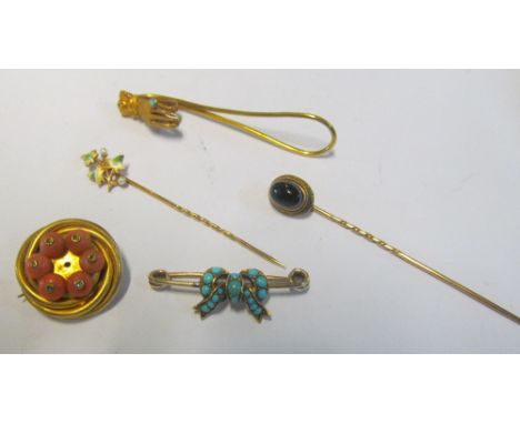 A gold coloured clip set hand with turquoise stone, turquoise set bow brooch, two stick pins and a circular brooch set coral