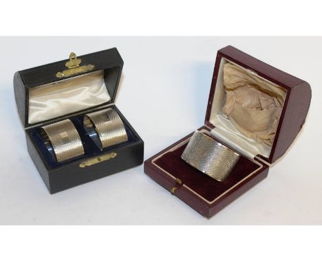 A pair of engine turned serviette rings, Birmingham 1912, cased, and another 1933 (3).