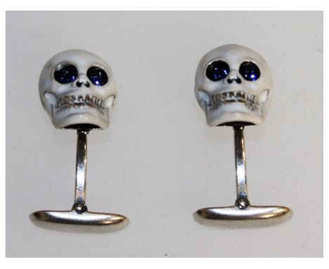 A pair of sterling silver and enamel cufflinks in the form of skulls.