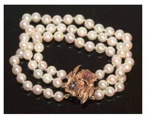 A three row pearl bracelet with gold and ruby clasp.