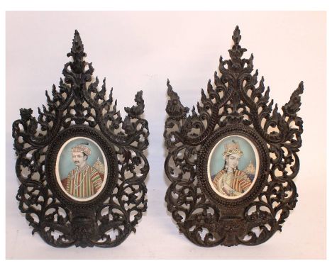 A very rare pair of Indian portrait miniatures on ivory, 10cms x 8cms, in a pierced and carved easel frame with dragons. 38cm