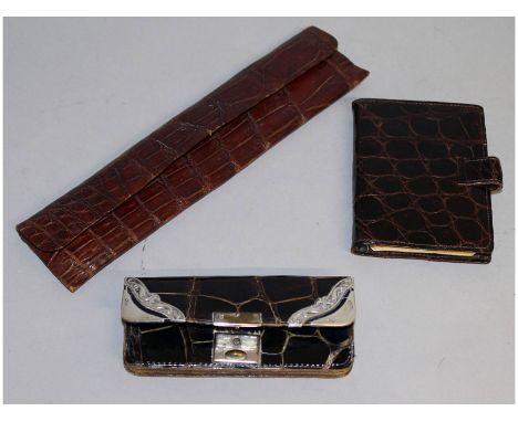 A silver mounted crocodile purse, a silver mounted comb in a leather case and a crocodile notebook (3).