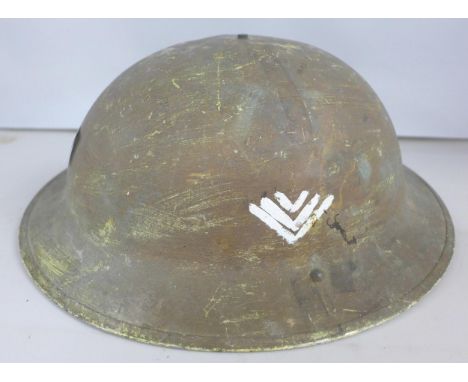 A British World War II Brodie pattern steel combat helmet, bearing regimental insignia