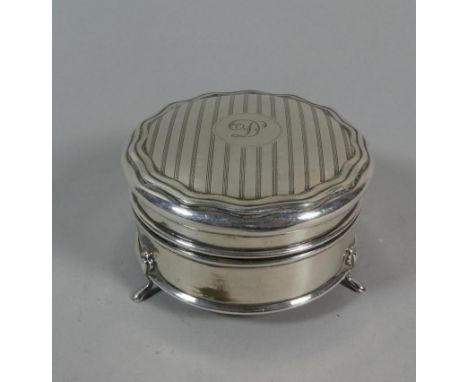 A Circular Silver Dressing Table Box on Three Feet. The Turned Circular Lid with Engine Turned Decoration and Monogrammed 'D'