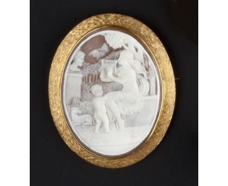 AN OVAL SHELL CAMEO BROOCH, carved to depict a seated lady playing the lyre, with a child and dog at her feet, in landscape s