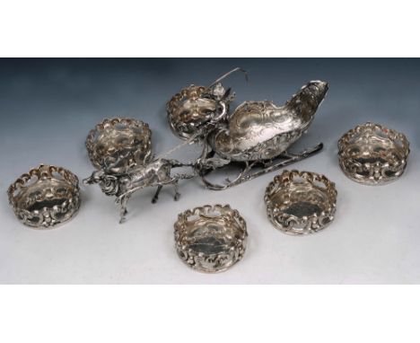 A CONTINENTAL CENTREPIECE in the form of a reindeer pulling a shell shaped sleigh with a seated cherub, 27cm long, with Germa