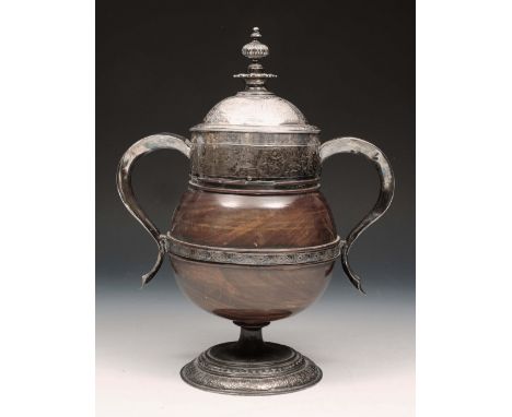 A 17TH CENTURY LIGNUM VITAE TURNED CUP AND COVER with white metal mounts, engraved with ecclesiastical panels, matching foot 