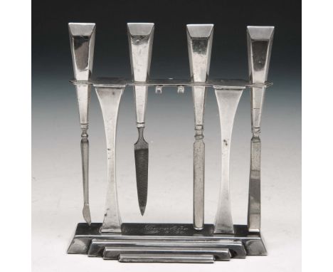 AN ART DECO STYLE VANITY SET CONSISTING OF a nail file, tweezers and two other tools on a free standing frame with a stepped 