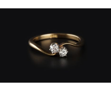 A DIAMOND TWO STONE CROSSOVER RING, obliquely claw set with old-cut diamonds, two colour precious metal mounted, stamped '18c