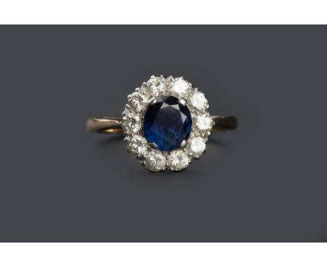 A SAPPHIRE AND DIAMOND CLUSTER RING, the oval mixed-cut sapphire claw set within a border of round brilliant-cut diamonds, tw