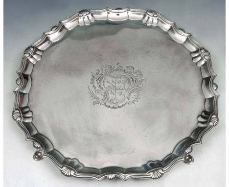A GEORGE II SILVER SALVER with a shell and scroll border and engraved cartouche standing on four cabriole legs with hoof feet