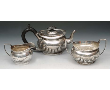 A LATE VICTORIAN THREE PIECE SILVER TEA SET, oval shaped teapot with fluted lower body, ebonised handle, matching finial, sug