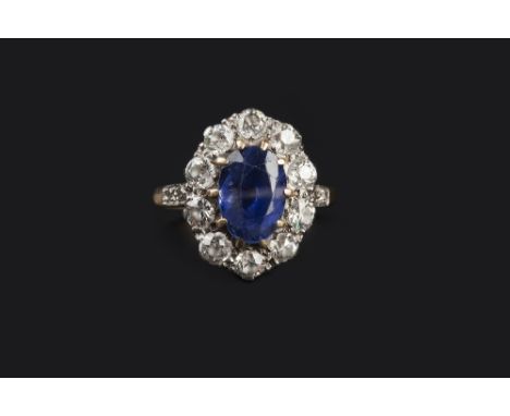 A SAPPHIRE AND DIAMOND CLUSTER RING, the oval mixed-cut sapphire claw set within a border of old-cut diamonds, between single