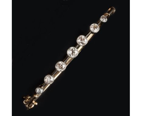 A DIAMOND SET BANGLE, of hinged oval form, the knife-edged mount spaced with seven graduated old-cut diamonds in millegrain c