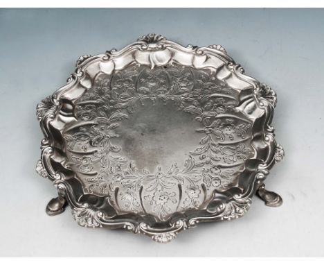 A LATE GEORGE II SILVER CARD TRAY with shell and scroll border and standing on three cabriole legs, 17cm diameter, with marks