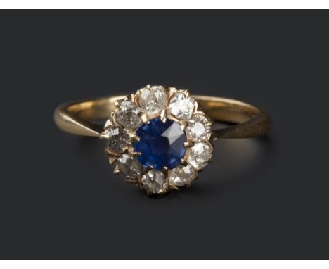 A SAPPHIRE AND DIAMOND CLUSTER RING, the cushion-shaped mixed-cut sapphire claw set within a border of nine old-cut diamonds,