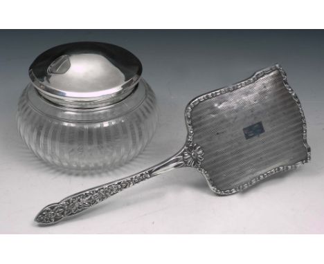 A SILVER BACKED HAND HELD MIRROR with engine turned and pressed foliate decoration, 29cm long, Birmingham 1961 by W.G. Sother