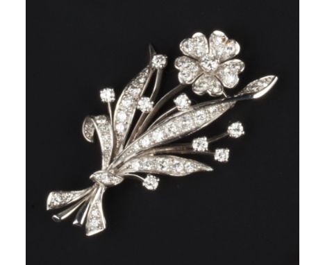 A DIAMOND FLORAL SPRAY BROOCH, modelled as a flowerhead cluster framed by a foliate spray with ribbon tie, set throughout wit
