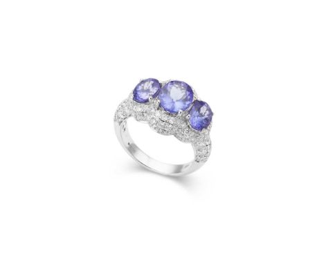 A Tanzanite and diamond ring claw-set with three oval-cut Tanzanites in a pavé-set round brilliant-cut diamond surround, mode