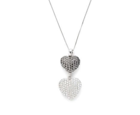 A black and colourless diamond heart pendant composed of two pavé-set black and colourless diamond hearts, unmarked, to an 18